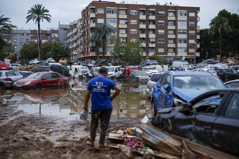 Un hombre junto a varios coches arrastrados por el agua tras el paso de la dana, en Paiporta. EFE/ Biel Aliño
