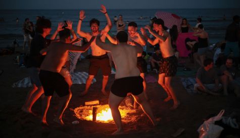 Un grupo de jóvenes baila en la playa de la Malvarrosa a la que han acudido miles de personas para celebrar con hogueras la tradicional Noche de San Juan.