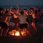 Un grupo de jóvenes baila en la playa de la Malvarrosa a la que han acudido miles de personas para celebrar con hogueras la tradicional Noche de San Juan.