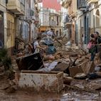 Imagen de archivo de vecinos intentando atravesar una calle en Paiporta cubierta de barro y enseres dos días después de la dana.