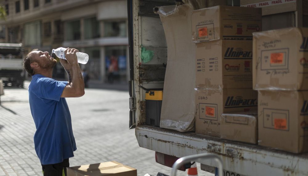 Un trabajador de una empresa de mudanzas bebe agua para combatir el calor en una calle del centro de Valencia. / EFE-Biel Aliño Un trabajador de una empresa de mudanzas bebe agua para combatir el calor en una calle del centro de Valencia. / EFE-Biel Aliño