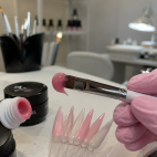 Aplicación de acryl gel sobre unas puntas de muestra en un salón de uñas.