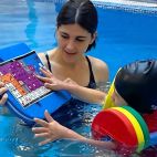 Una terapeuta trabaja con un niño en el agua mediante un sistema de comunicación aumentativa, en una sesión de neurorrehabilitación pediátrica. / Vithas