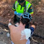Agente de la Guardia Civil atienden a uno de los ciclistas heridos tras la caída múltiple durante la prueba en Estivella./ Guardia Civil