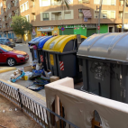 Contenedores de basura y reciclaje en una calle de Torrent, con residuos y cartones acumulados junto a ellos. / EPDA