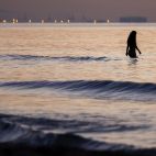 Una jove banyant-se a trenc d'alba en la platja de la Malvarrosa, en València.