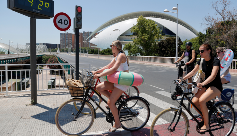 Imagen de archivo de varias jóvenes transportando sus flotadores en bici al paso de un termómetro que marca 42 grados en València. EFEManuel Bruque