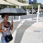 En la imagen una mujer se protege con un paraguas del intenso sol esta tarde en la plaza América de Valencia. / EFE/Manuel Bruque