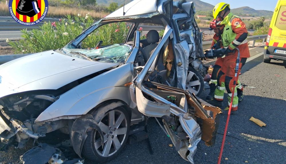 Los bomberos del Consorci Provincial de Bombers de València trabajan en el vehículo siniestrado tras la colisión entre un coche y un camión en la A-7, a la altura de Aielo de Malferit. / Consorci Provincial de Bombers de València