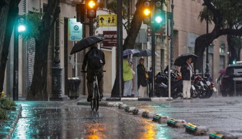 Un ciclista circula con paraguas durante una tormenta. / EFE-Manuel Bruque-Archivo
