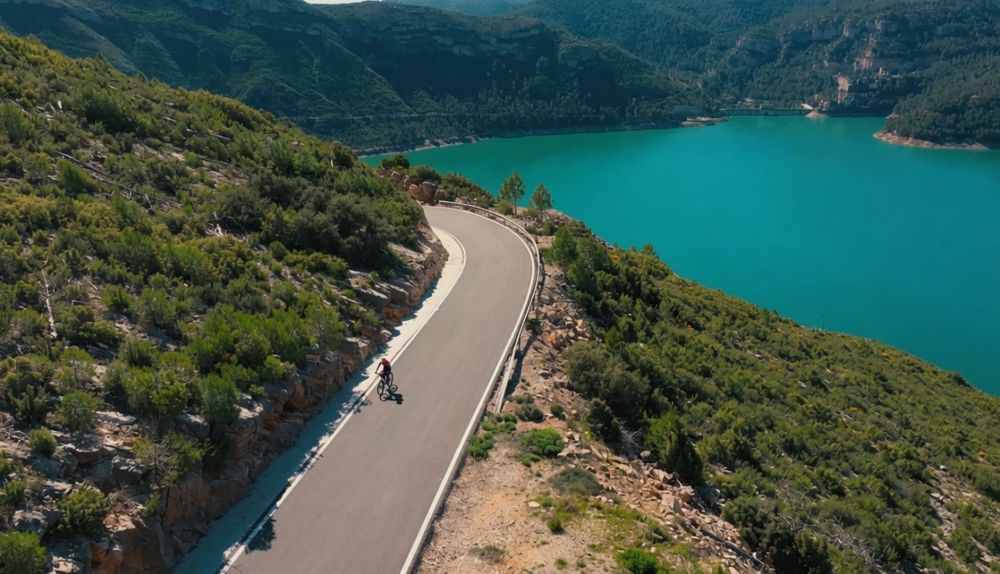 Un ciclista recorre la carretera vora l'embassament de Benagéber, escenari on arranca la ruta de 'Valencians sobre rodes'. / À Punt Un ciclista recorre la carretera vora l'embassament de Benagéber, escenari on arranca la ruta de 'Valencians sobre rodes'. / À Punt