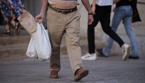 Un hombre camina por una calle de València portando bolsas de la compra.