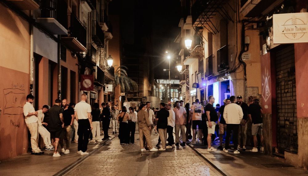 Grupos de amigos y viajeros se reúnen al caer la noche a las puertas de los locales de una calle empedrada del centro histórico. Grupos de amigos y viajeros se reúnen al caer la noche a las puertas de los locales de una calle empedrada del centro histórico.
