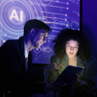 Dos profesionales consultan una tableta ante una pantalla con el símbolo de la inteligencia artificial.