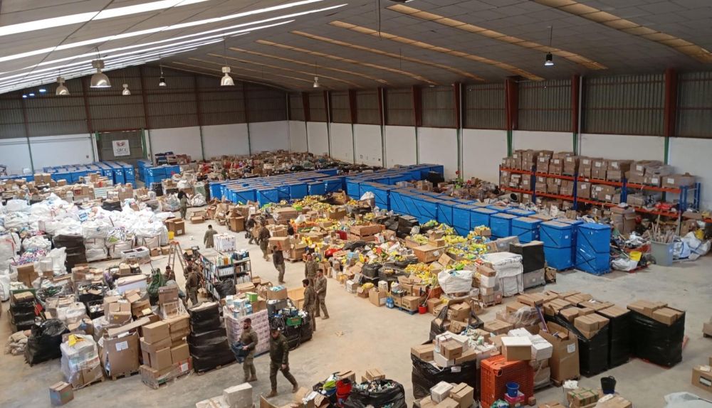 Militares y voluntarios clasifican productos donados en una nave tras la dana de 2024.