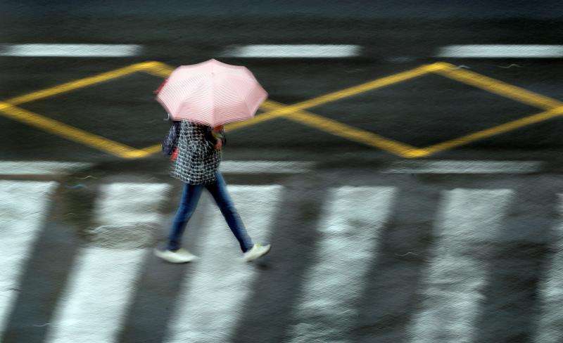 En la imagen, una persona se protege de la lluvia en la ciudad de València, hoy a primera hora del día. EFE
