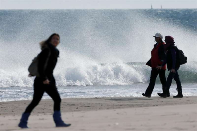 Dos personas pasean por la playa en un día de fuerte viento. - EFE