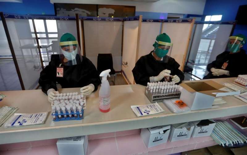 Varias personas con trajes de protección contra el coronavirus revisan el material de trabajo dentro de la zona roja en el aeropuerto internacional Jardines del Rey en Cayo Coco, Cuba. EFE/Ernesto Mastrascusa/Archivo
